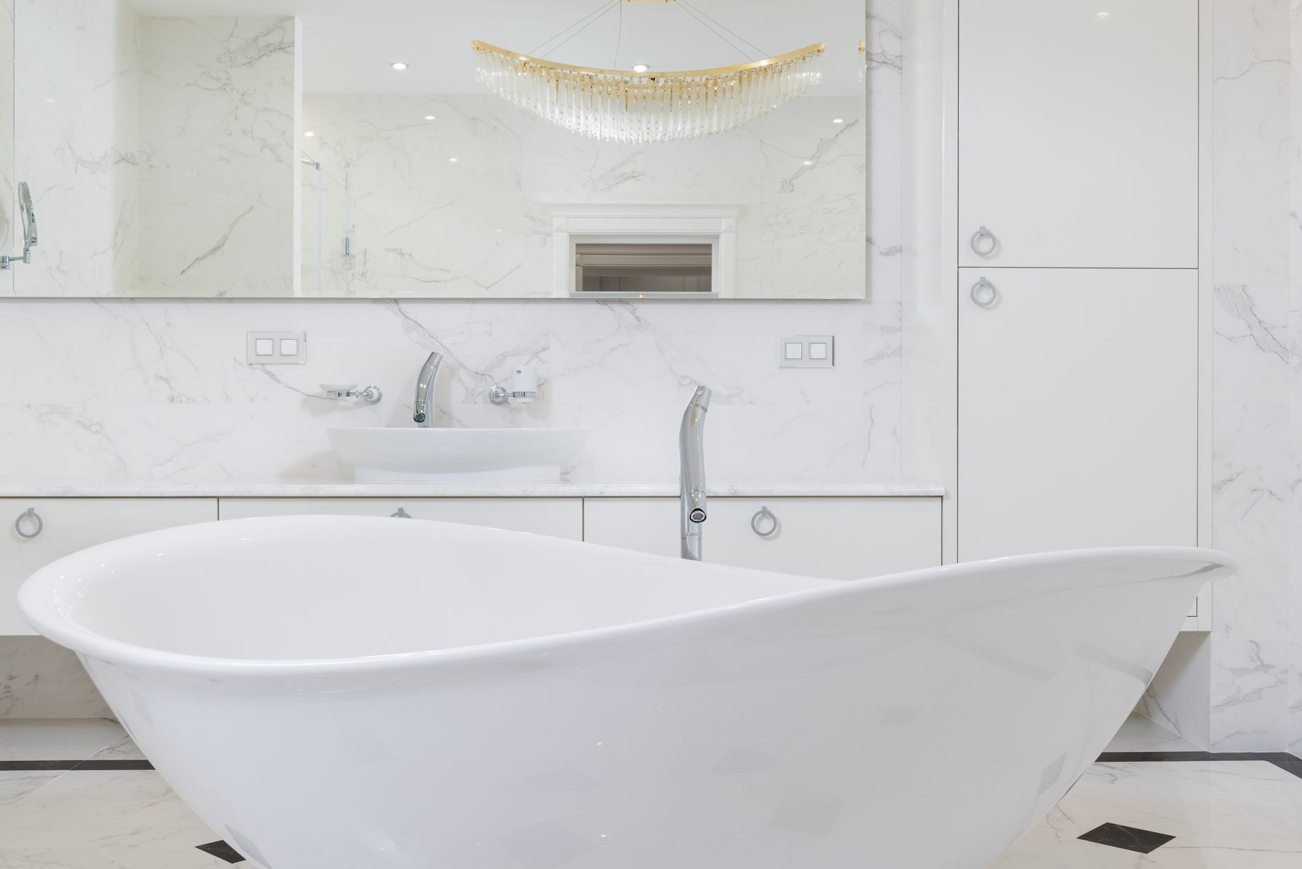 A white marble bathroom with a large mirror