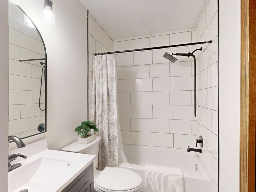 Sleek and clean modern bathroom with white tiles and black fixtures.